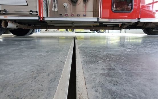 Öppen golvränna under ett rött servicefordon i verkstad